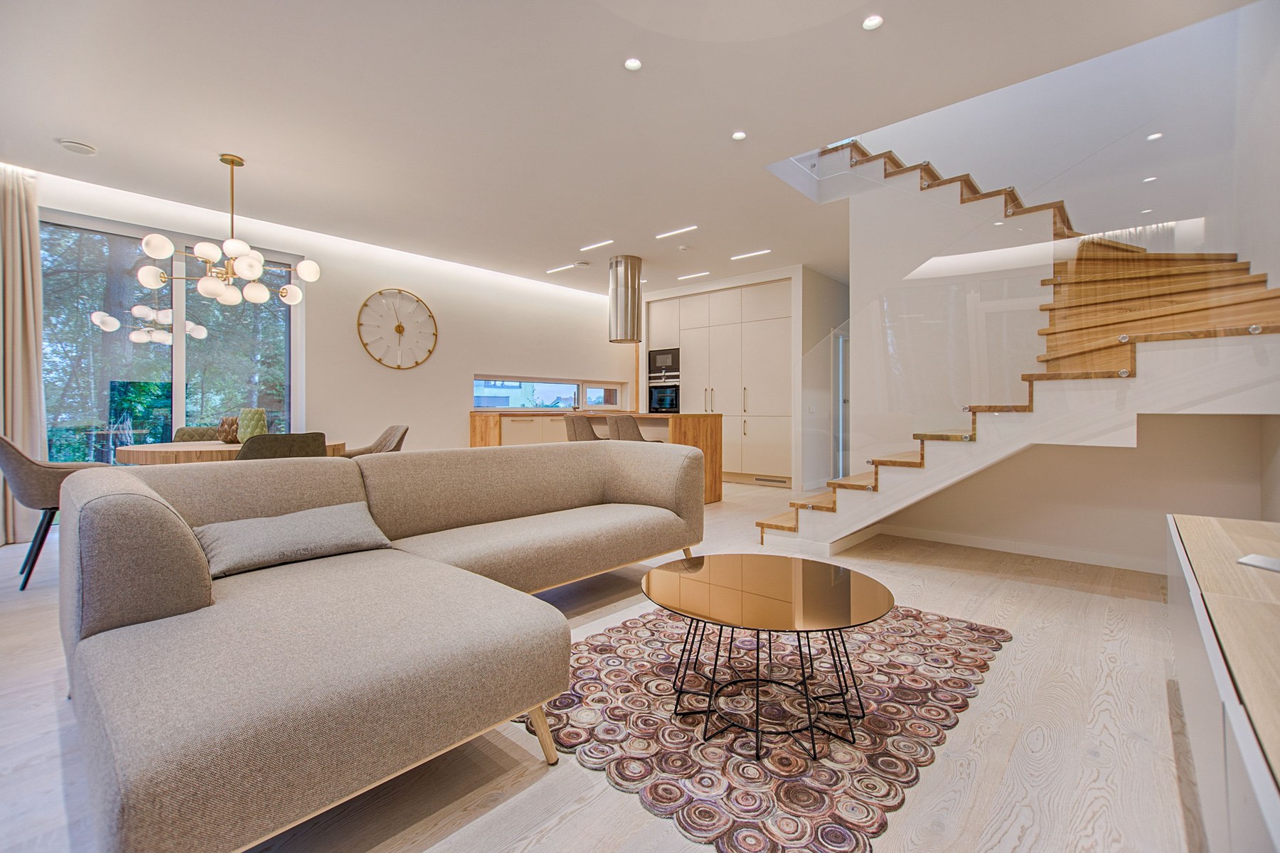 Bright modern living room with sofa and staircase in warm neutral tones